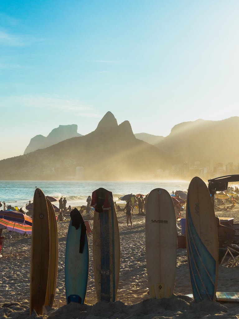 Surfboards lined up on Ipanema Beach in Rio de Janeiro at sunset with mountains in the background.